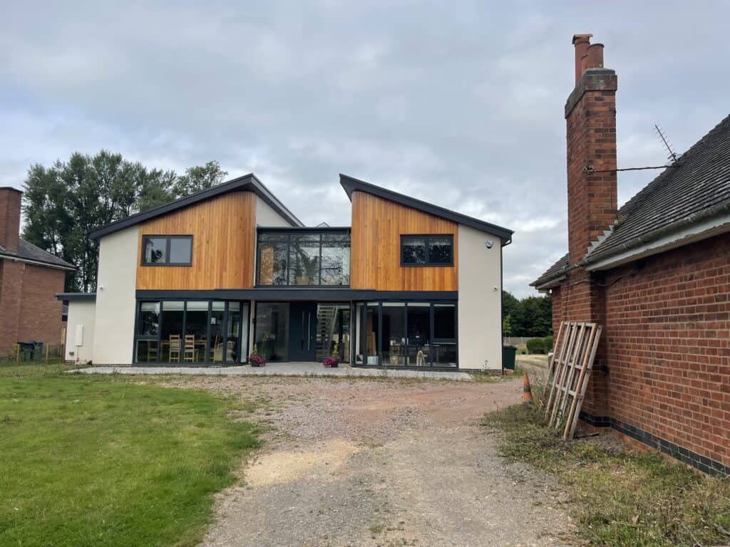 Contemporary modern residential house with large glass windows and wooden exterior cladding.